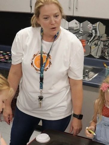 Teacher engaging with children in a classroom setting.