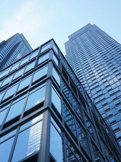 Looking up at modern glass skyscrapers against a clear sky.