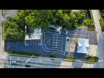 Aerial view of a parking lot with two buildings and surrounding greenery.