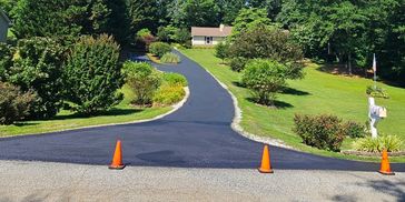 Newly paved driveway with orange cones blocking entry.