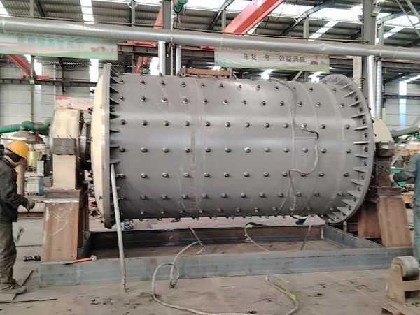 Workers assemble a large industrial cylindrical machine in a factory.