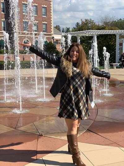 Woman posing happily by water fountains outdoors.