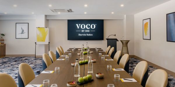 Modern conference room with a long table, chairs, and presentation screen.