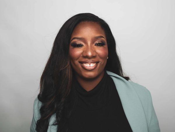 Smiling woman with long hair and a light blue blazer.