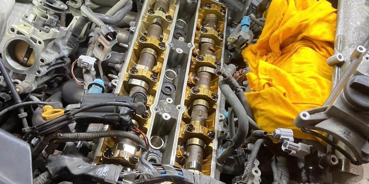 Close-up of a car engine's camshaft area with a yellow cloth nearby.