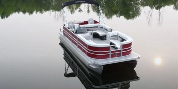 A red and white pontoon boat floating on calm water with reflections.