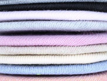 Prendas de punto apiladas en diferentes colores suaves.