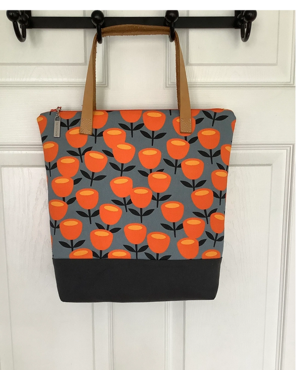 Handbag with top zip enclosure. Exterior of bag includes a traditional "Ms Whimsy" print paired with