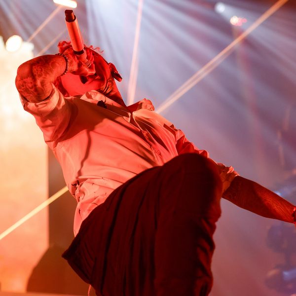 Performer passionately singing on stage under dramatic lighting.
