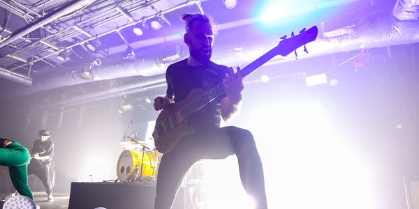 Musician passionately playing electric guitar during live concert.