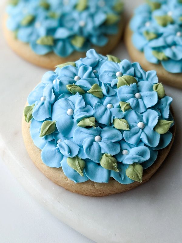 A sugar cookie with blue hydrangea flowers on top