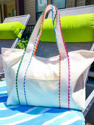White tote bag with colorful trim on lounge chair.