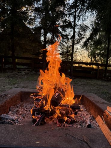 A vibrant campfire burning in a rustic outdoor setting at dusk.