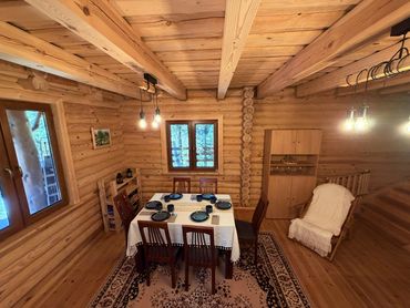 Cozy wooden dining room with table set for six in a rustic cabin.