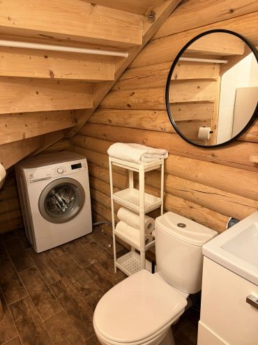 Cozy rustic bathroom with washing machine and wooden walls under staircase.