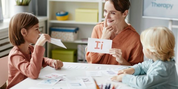 Teacher holds a flashcard while kids learn letters in a classroom.