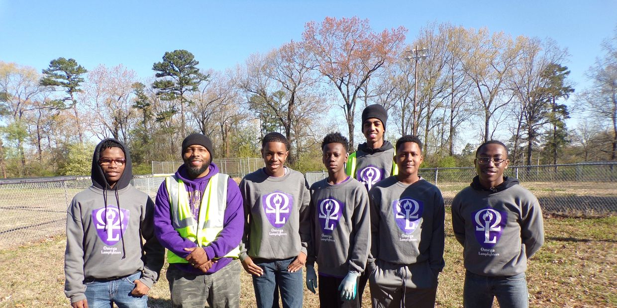 Group of seven people outdoors with matching shirts and a safety vest.