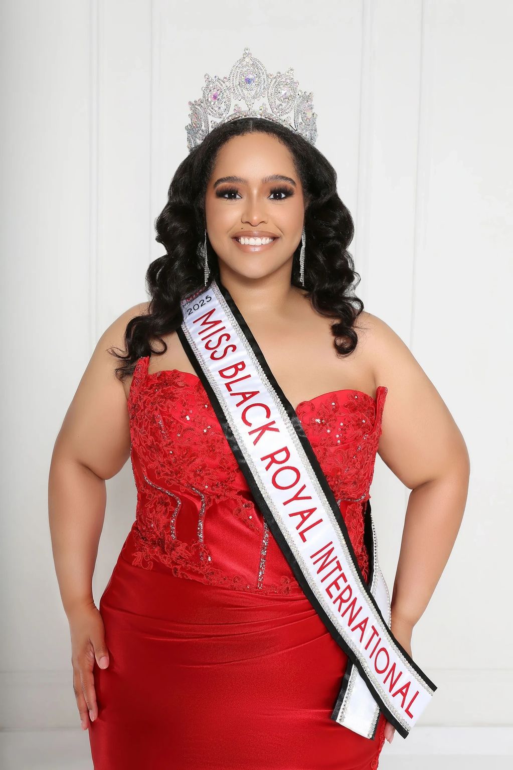 Beauty queen in a red gown with a sash and crown.