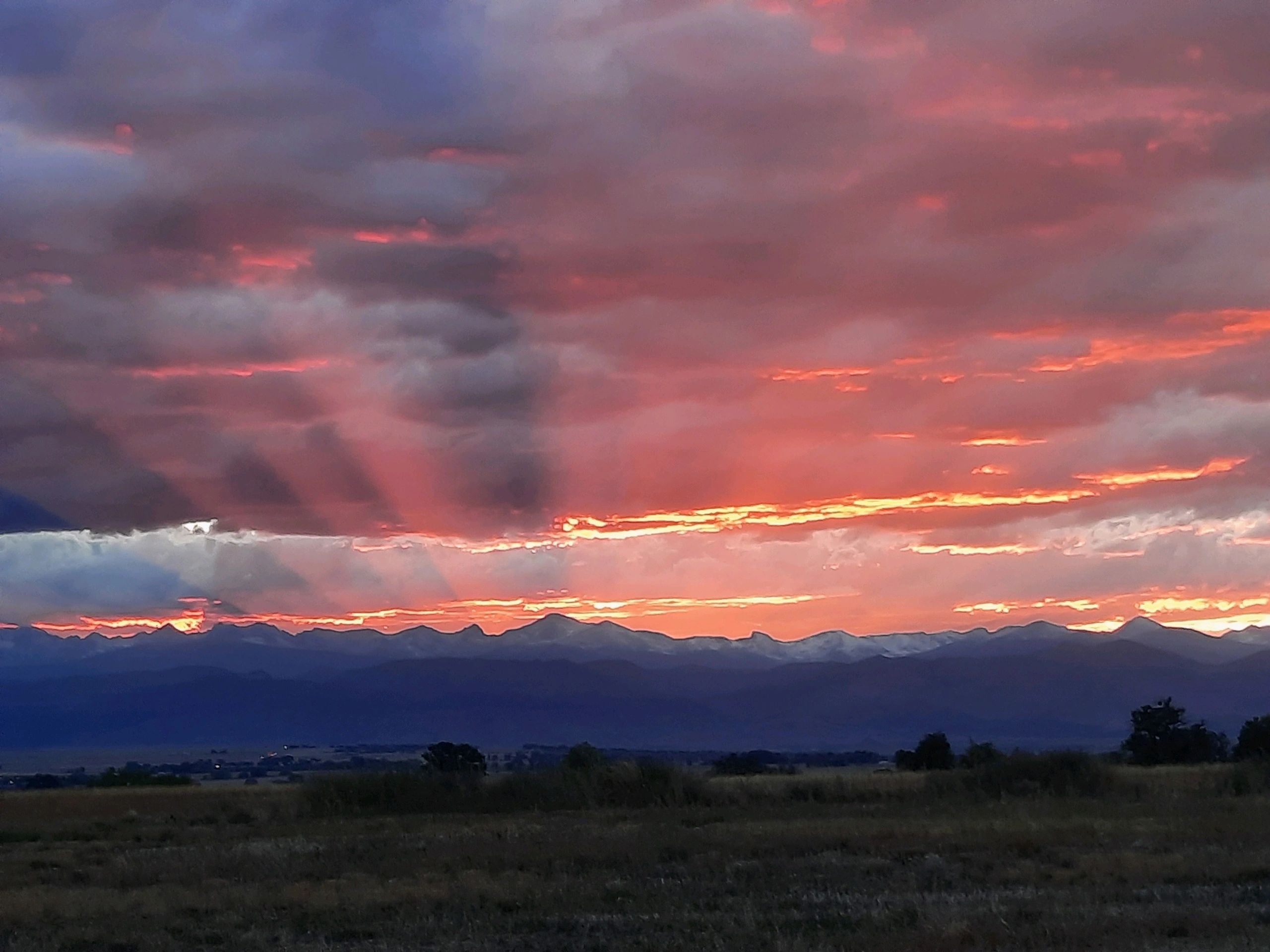 Sunset in Rocky Mountains with peaks casting shadows through the sun rays.