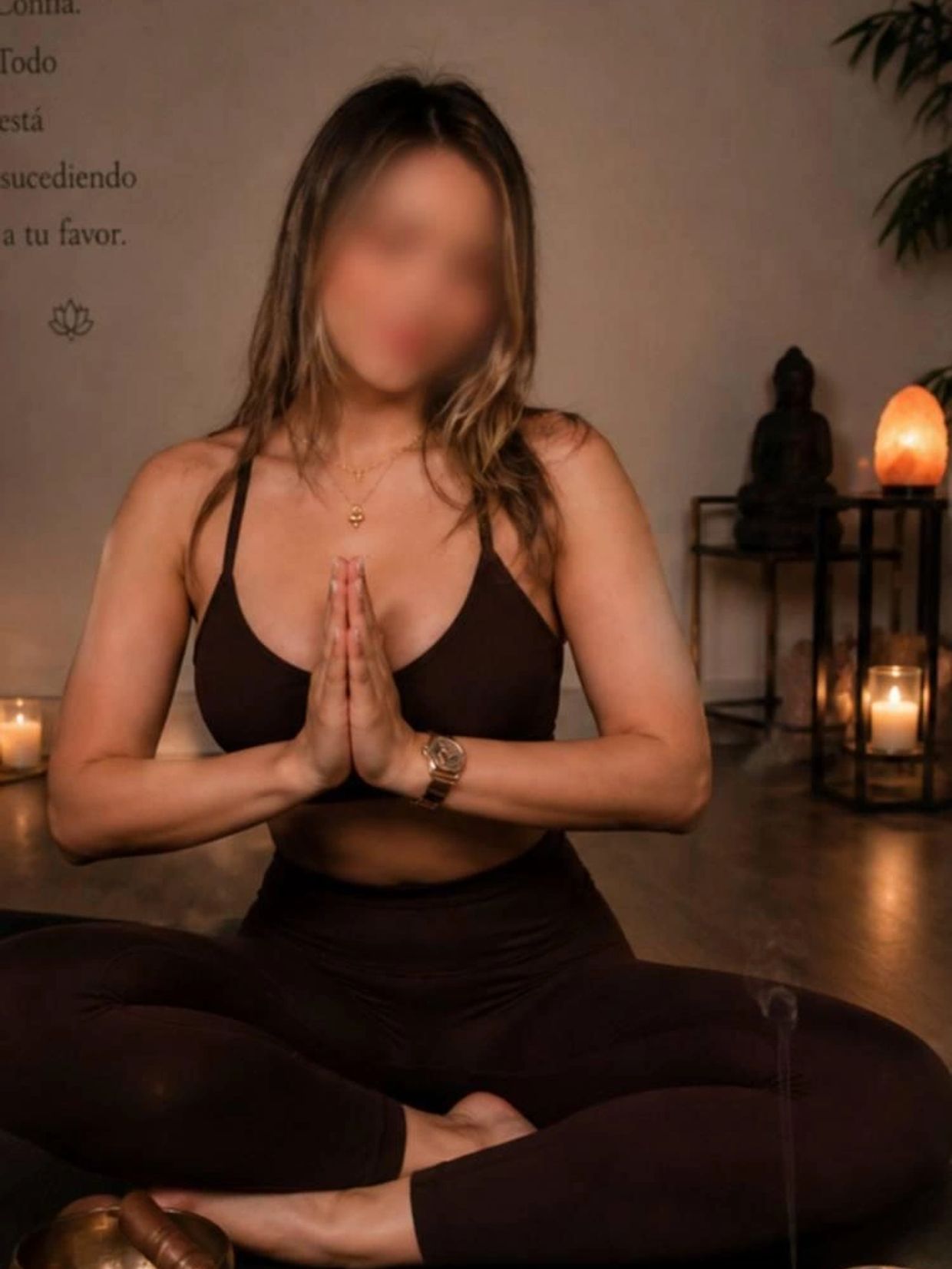 Woman practicing yoga in a serene, candle-lit room with hands in prayer pose.