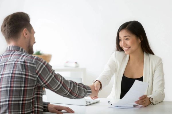 Smiling asian businesswoman handshaking businessman hiring candidate at job interview.