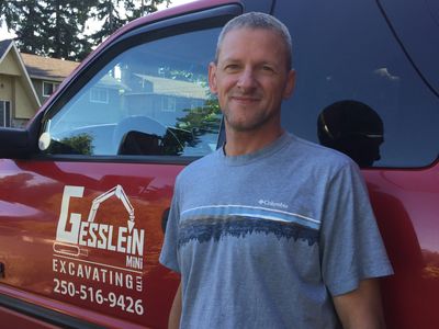 Man standing beside a red excavation truck.