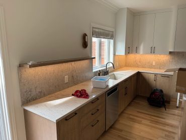 Cuisine moderne avec plan de travail lumineux et armoires en bois.