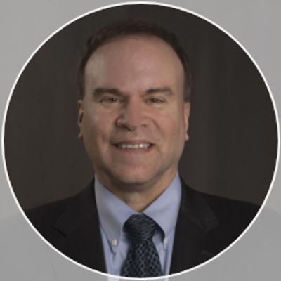 Professional headshot of a smiling man in a suit and tie.
