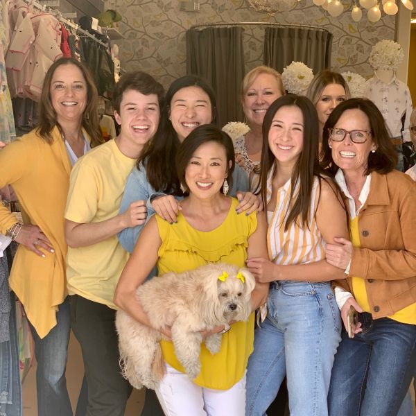 Group of people smiling, one holding a dog with yellow bows.
