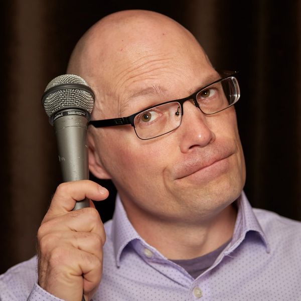 Man holding a microphone, looking thoughtful.