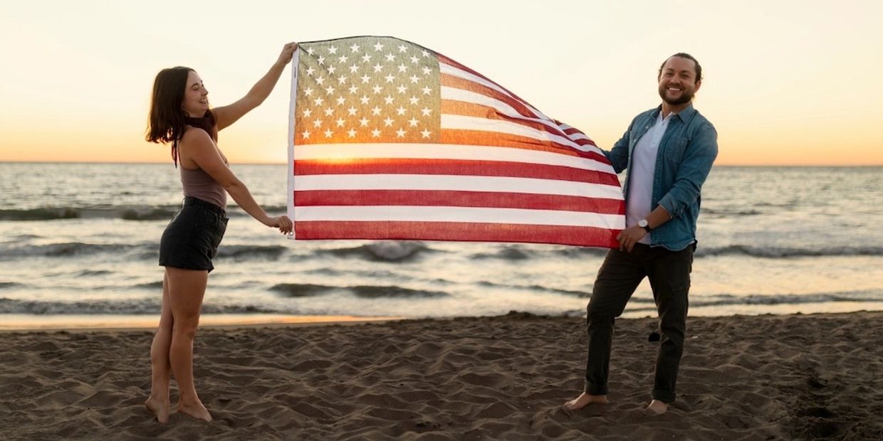Couple on a beach with American flag at sunset