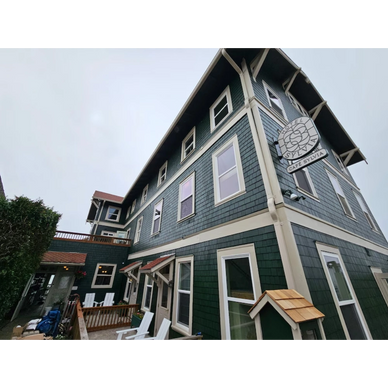 Full front view of The Sylvia Hotel in Newport, OR, showcasing restored siding, trim, and windows by