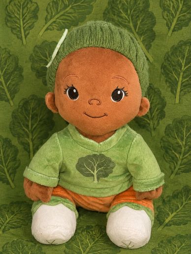 A plush doll dressed in green with a tree design on its shirt.