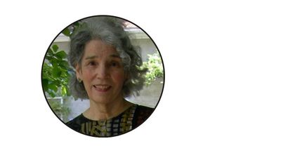 Portrait of a smiling elderly woman with curly gray hair.