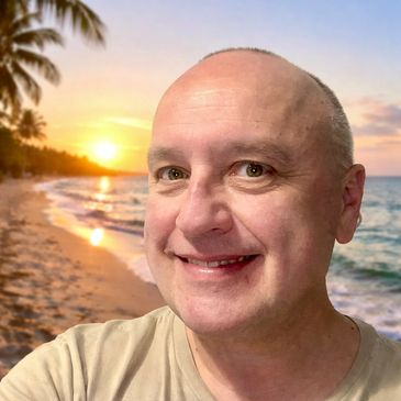 Smiling man taking a selfie at a tropical beach sunset.