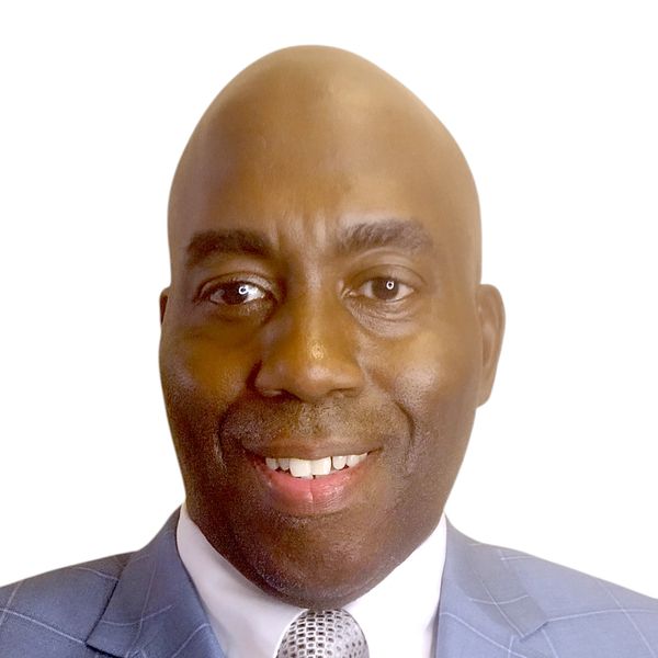 Smiling man in a blue suit and tie against a white background.