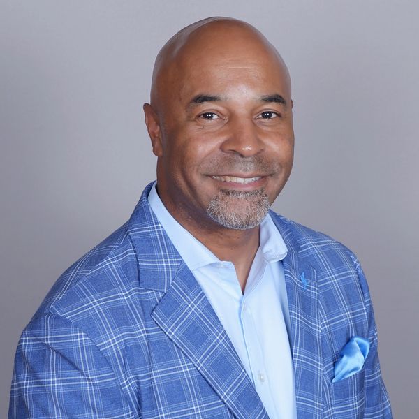 Smiling man in a blue checkered blazer with a pocket square.