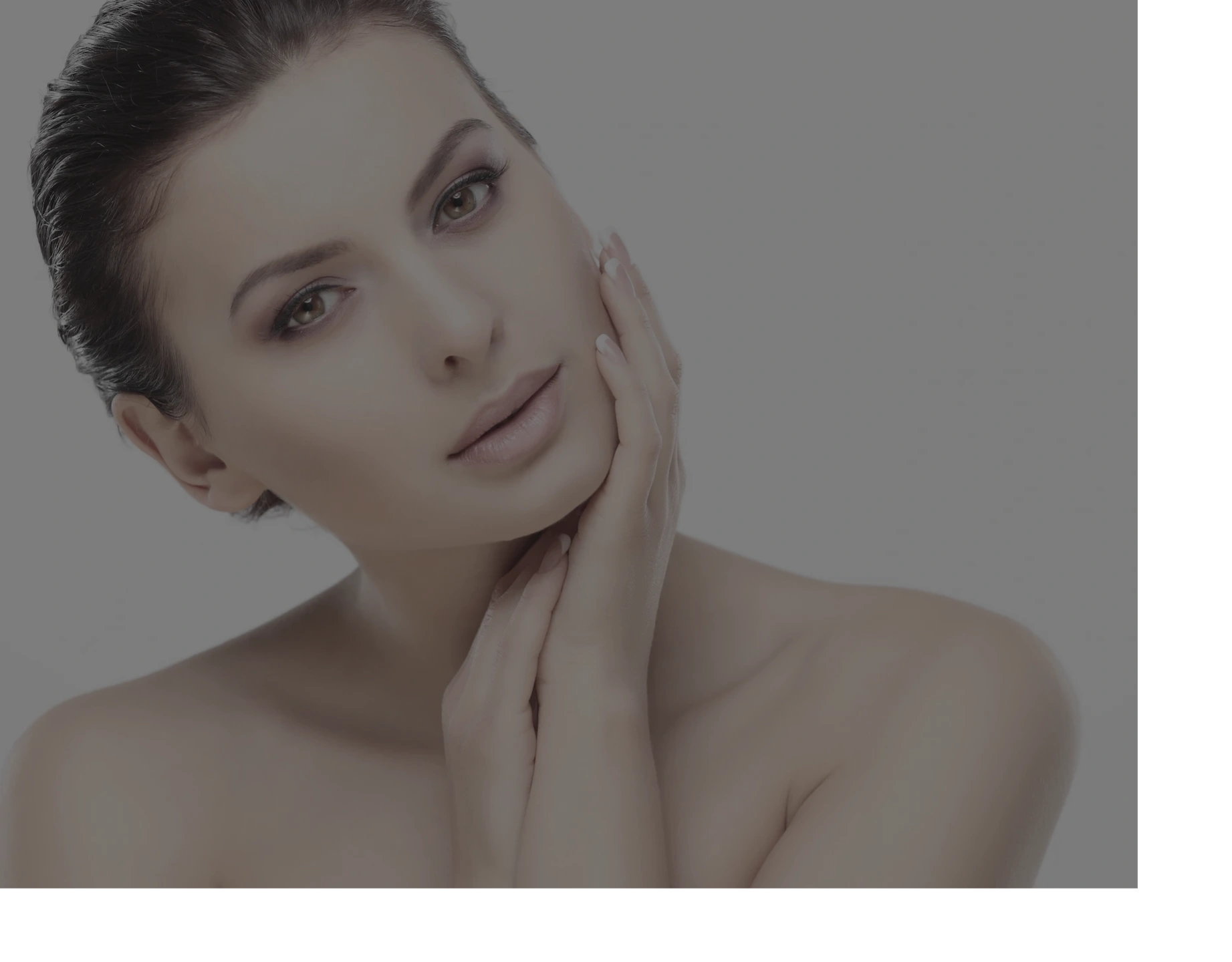 Close-up of a woman with flawless skin gently touching her face.