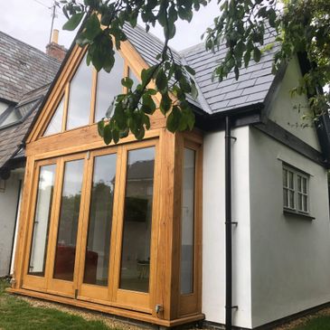 Modern wooden-framed glass extension on a traditional house.