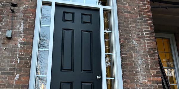 Black front door with glass panels on a brick house.