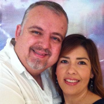 A smiling couple posing closely together for a photo.