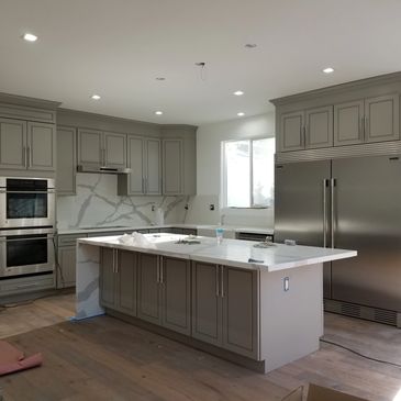 Modern kitchen with gray cabinets and marble countertops.