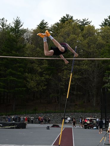 Athlete clearing the high jump bar mid-air during a track event.