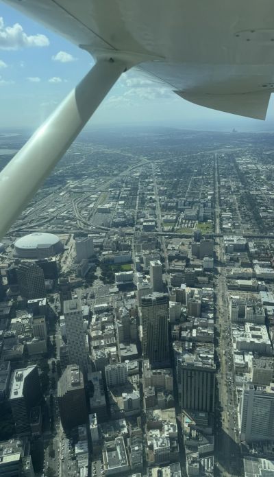 Aerial view of a city under an airplane wing on a clear day.