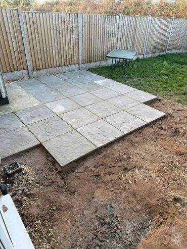 Partially completed patio with paving stones and adjacent dirt area.