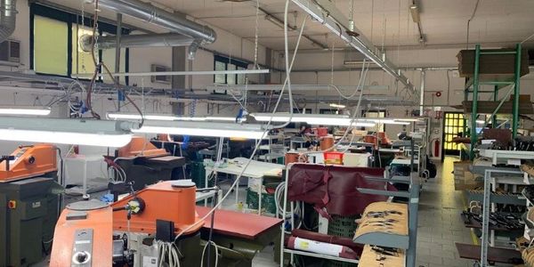 Inside a spacious garment factory with sewing machines and fabric.