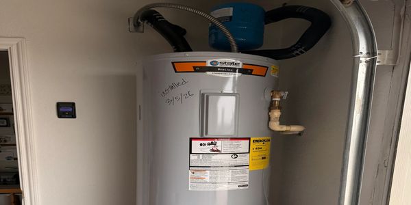 New water heater installed on 02/15/26 with visible piping and labeling.