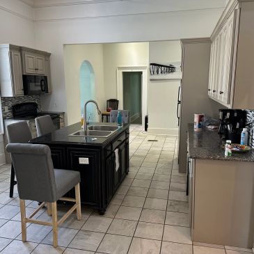 Modern kitchen with island, granite countertops, and tile flooring.