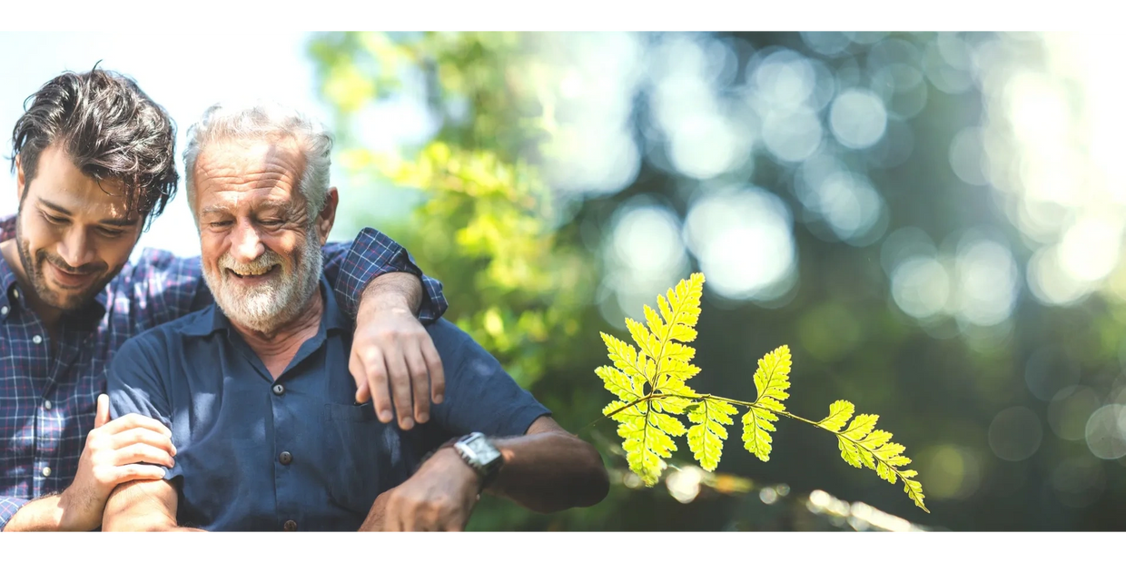 Elderly man enjoying the companionship of his son in an outdoor setting.
