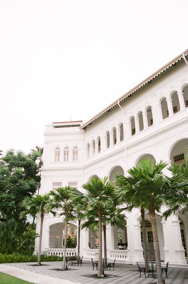 Facade of Raffles Hotel Singapore with palm trees
